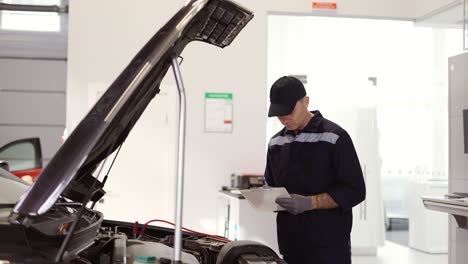 Mechaniker-In-Einer-Autoreparaturaufnahme,-Überprüfung-Des-Motors-Mithilfe-Eines-Tablets