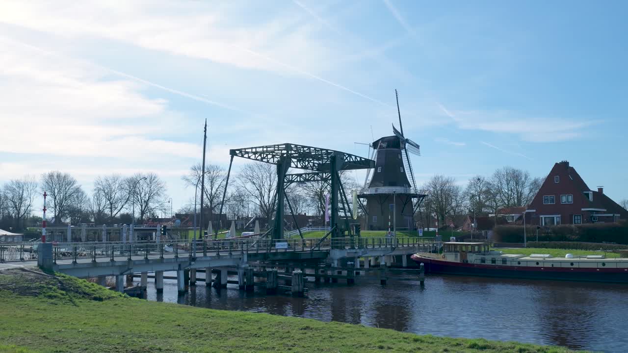 Traditionelle holländische Windmühle und Zugbrücke über einem Kanal an einem sonnigen Tag