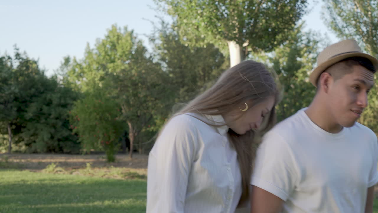 Young couple walking at public park. Happy latin man and Caucasian woman in love
