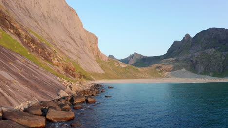 Drone-shot-of-remote-Horseid-sand-beach-surrounded-by-steep-cliffs-in-Norway-Lofoten