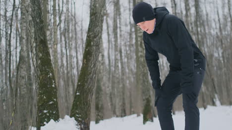 un joven que corría por la mañana en el bosque invernal estaba cansado, se detuvo para descansar y siguió corriendo. recuperó sus fuerzas, superó la fatiga y continuó corriendo. perseverancia y superación de las debilidades. esforzándose hacia adelante. camara lenta. estilo de vida saludable