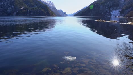 cênico fiorde veafjorden, noruega contrastado por resíduos plásticos flutuando perto da costa