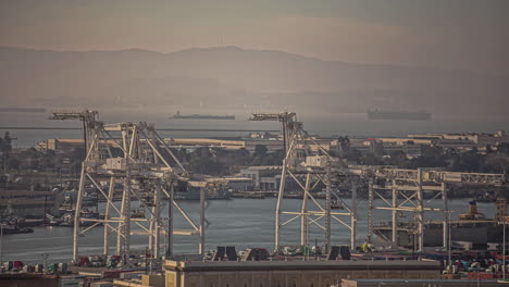 Overview-of-the-port-of-Oakland-at-sunset-in-timelapse-in-San-Fransisco,-California,-USA-with-the-view-of-a-mountain-range-in-the-background