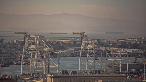 overview of the port of oakland at sunset in timelapse in san fransisco, california, usa with the view of a mountain range in the background