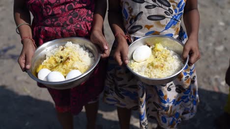 poor and hungry asian children holding rice and eggs in plate at sunny day, closeup shot