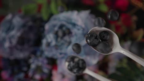 blueberries falling onto white spoon and bouncing off blue flower