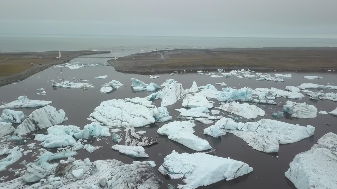 Flygbana över isblock som flyter i glaciärsjön Jökulsárlón nära glaciären Breiðamerkurjökull en mulen dag, Vatnajökull nationalpark, Island