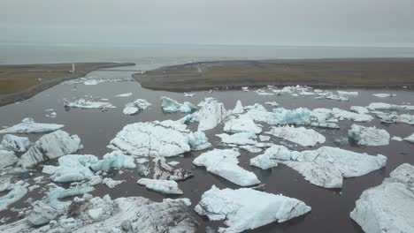 Aerial-orbit-of-ice-bocks-floating-in-Jökulsárlón-glacial-lake-near-Breiðamerkurjökull-glacier-on-an-overcast-day,-Vatnajökull-National-Park,-Iceland