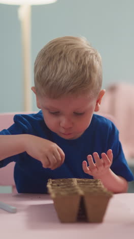 curious little boy puts seeds with mother help and bored sister in living room slow motion. woman with children plants seedlings. domestic life