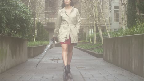 young beautiful latin woman dancing around with an umbrella in the city while listening to music