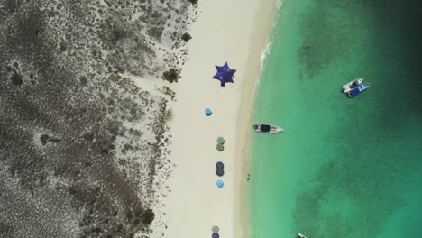 The-stunning-cayo-de-agua-in-los-roques-with-boats-and-clear-blue-waters,-aerial-view