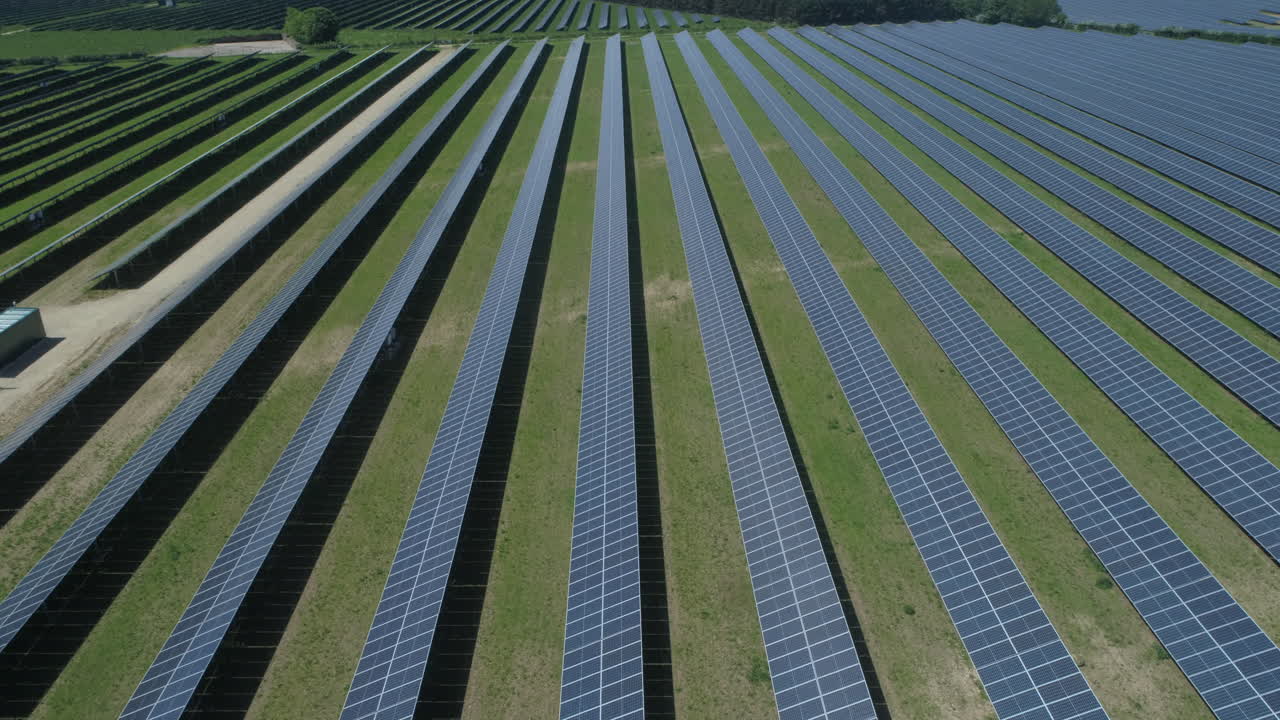 съемка с беспилотника, летящего вниз по полю солнечных панелей на солнечной ферме в яркий солнечный день