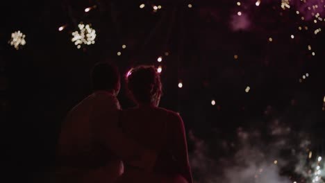silhouette of married couple in front of fireworks display at wedding
