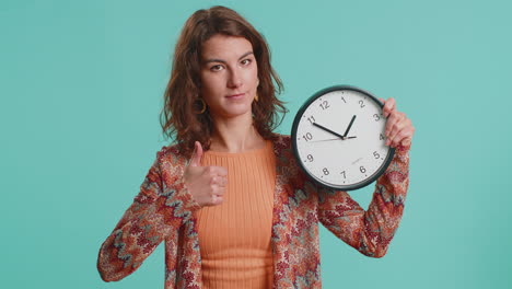 femme montrant l'heure sur l'horloge du bureau mural, ok, pouce haut, approuver, montrer du doigt à la caméra, votre temps