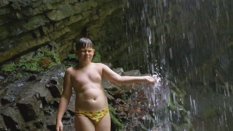 boy under a waterfall in a cave