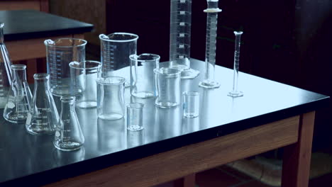 inclinándose hacia arriba para revelar un banco de laboratorio negro con una variedad de cristalería química en el laboratorio de química de la escuela secundaria