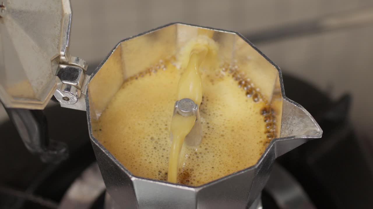 Bubbling moka pot releasing fresh coffee in slow motion from the spout