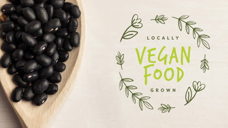 animation of vegan food text in green over fresh organic black beans on wooden boards