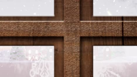 Christmas-tree-and-wooden-window-frame-against-snow-falling-over-multiple-houses-on-winter-landscape