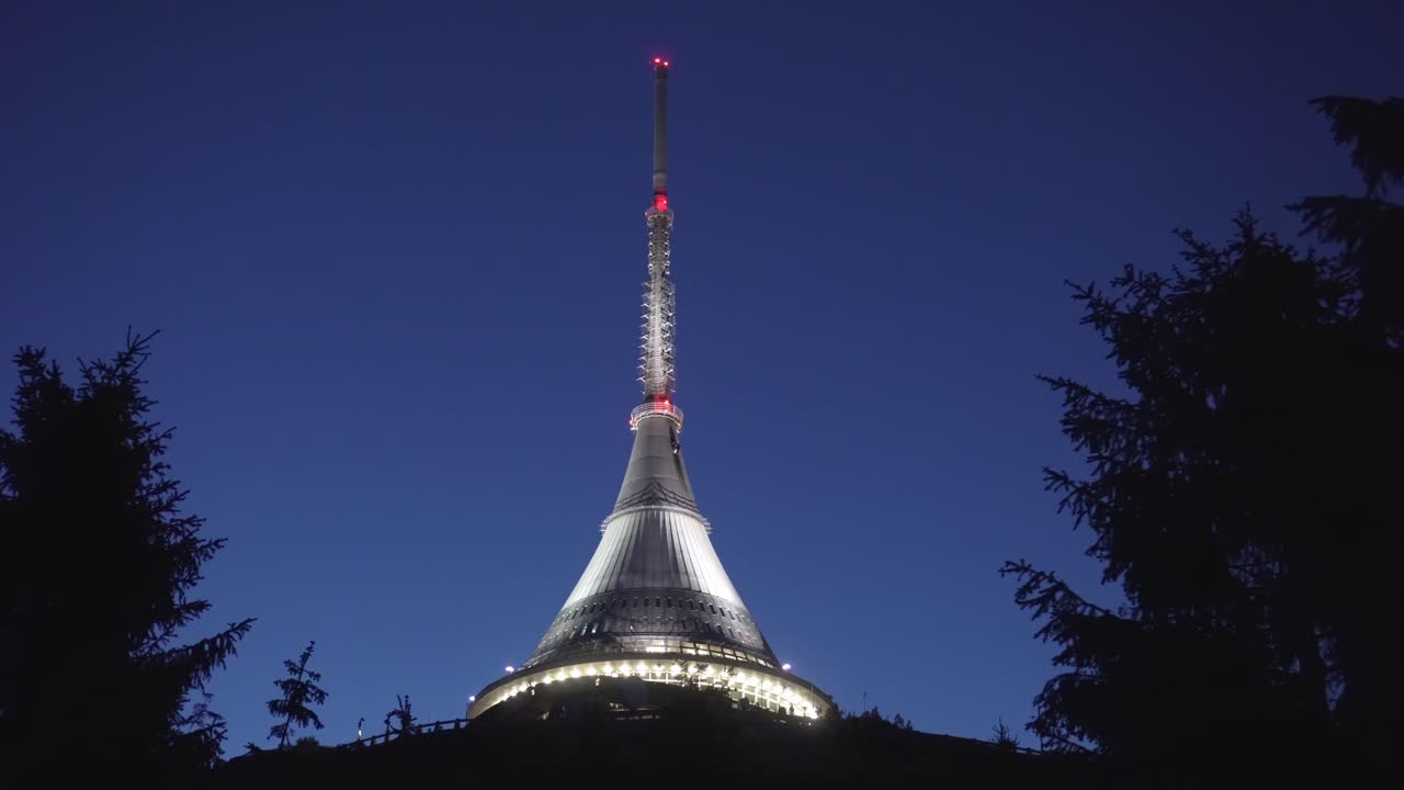 Night shot of Jested Tower with hotel and restaurant, sliding right with trees in foreground, beautiful cinematic view, Czech Republic