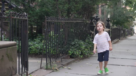 Dolly-shot-of-a-little-boy-smiling-and-walking-along-the-sidewalk-up-to-his-friend's-house-with-a-piece-of-paper-in-his-hand