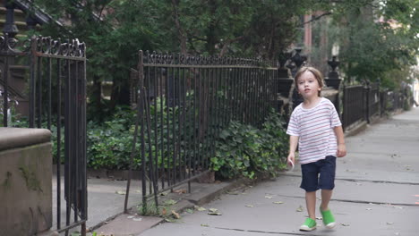 dolly shot of a little boy smiling and walking along the sidewalk up to his friend's house with a piece of paper in his hand