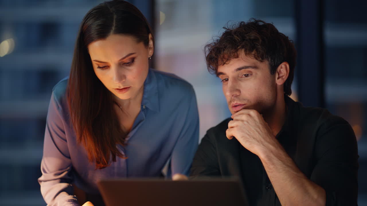 Businesswoman consulting man colleague working at laptop overtime closeup