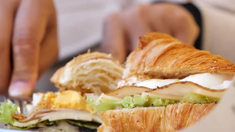 woman eating a croissant sandwich