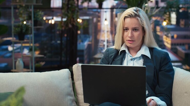 Revisione incerta dello schermo del laptop da parte di una donna d'affari in uno spazio di lavoro sul tetto