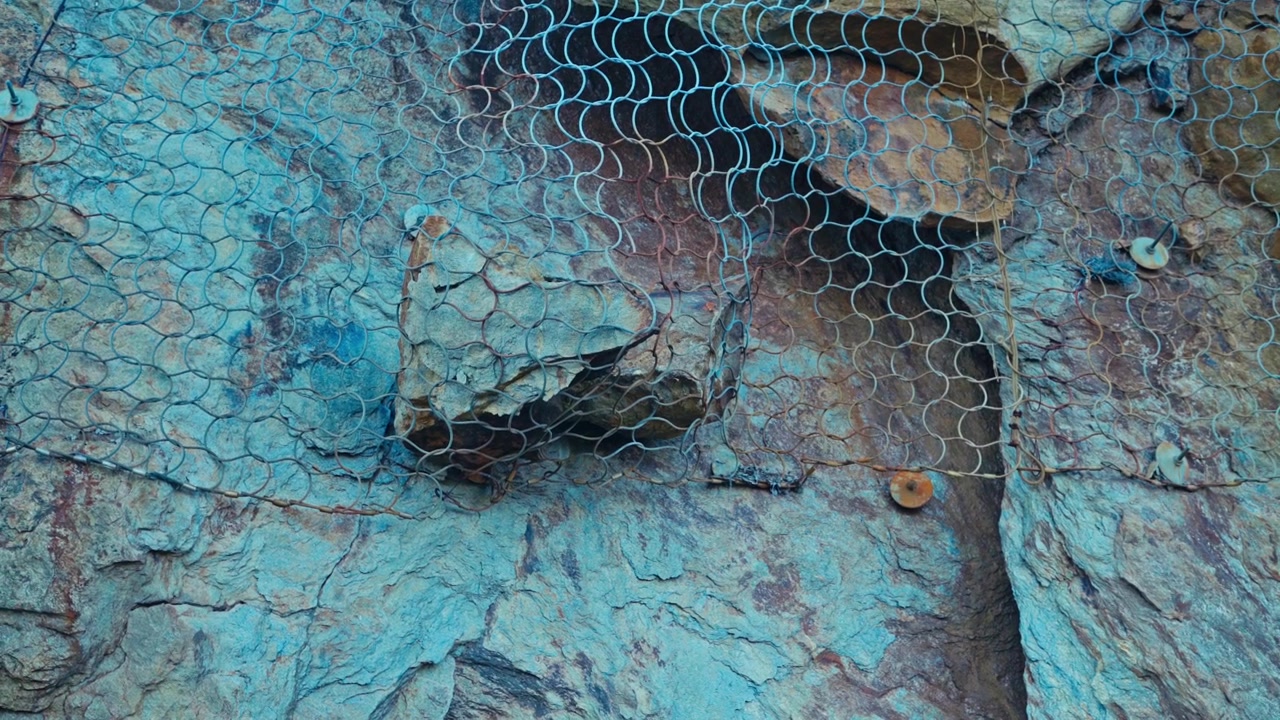 Rete metallica si estende sulla costa rocciosa, aggiungendo una texture aspra al tranquillo paesaggio costiero a Strøksnes, Comune di Sørfold, Nordland, Norvegia - Primo piano