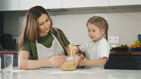 mother and daughter in kitchen prepare dough for cake