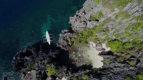 top aerial view of boat anchored at hidden beach on rocky coastline