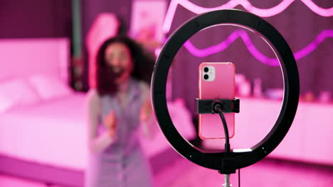 woman using a ring light with a phone in a bedroom
