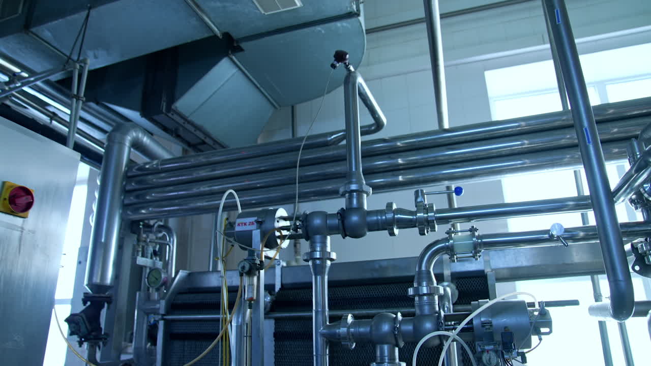 Silver stainless pipelines at a dairy factory. Tubes and pipes of different diameter and controller box in the modern milk enterprise. Close up.