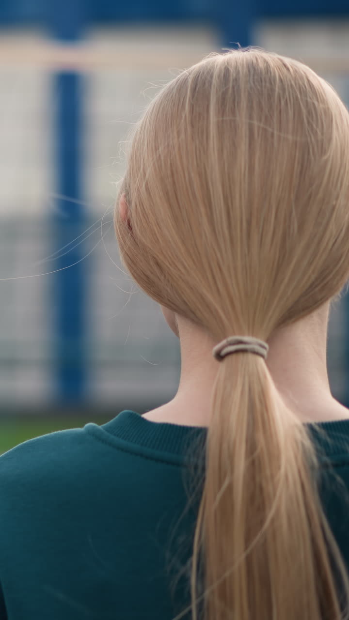 푸른색과 초록색 스웨터를 입은 두 여인이 배구장 위에 서서, 카레드 셔츠를 입은 코치가 배구를 팔 에 들고 지시하는 것을 지켜보고 있습니다. 배경은 약간 흐릿합니다.