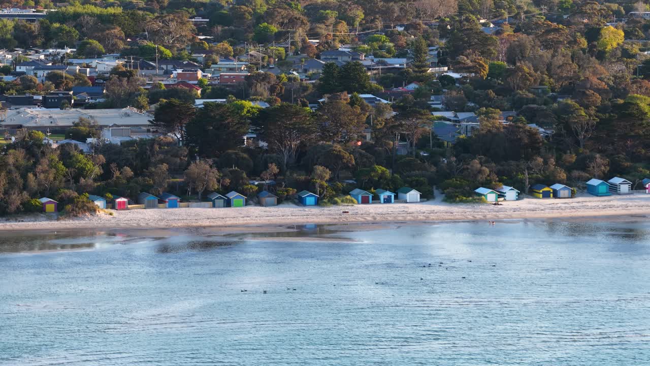 Høyt vinkel flyfoto med drone av fargerike strandhytter langs en sandstrand i Australia