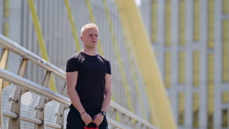 young athletic caucasian man does an outdoor workout in an urban environment