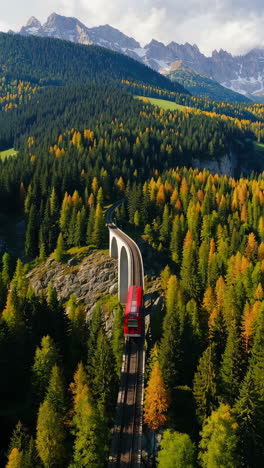 red train on a scenic mountain viaduct in an autumn forest