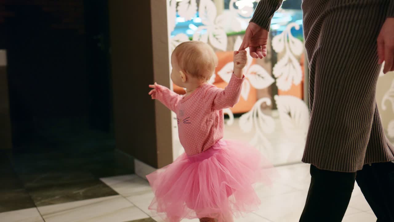 Bambina felice che impara a camminare tenendo la mano della madre.