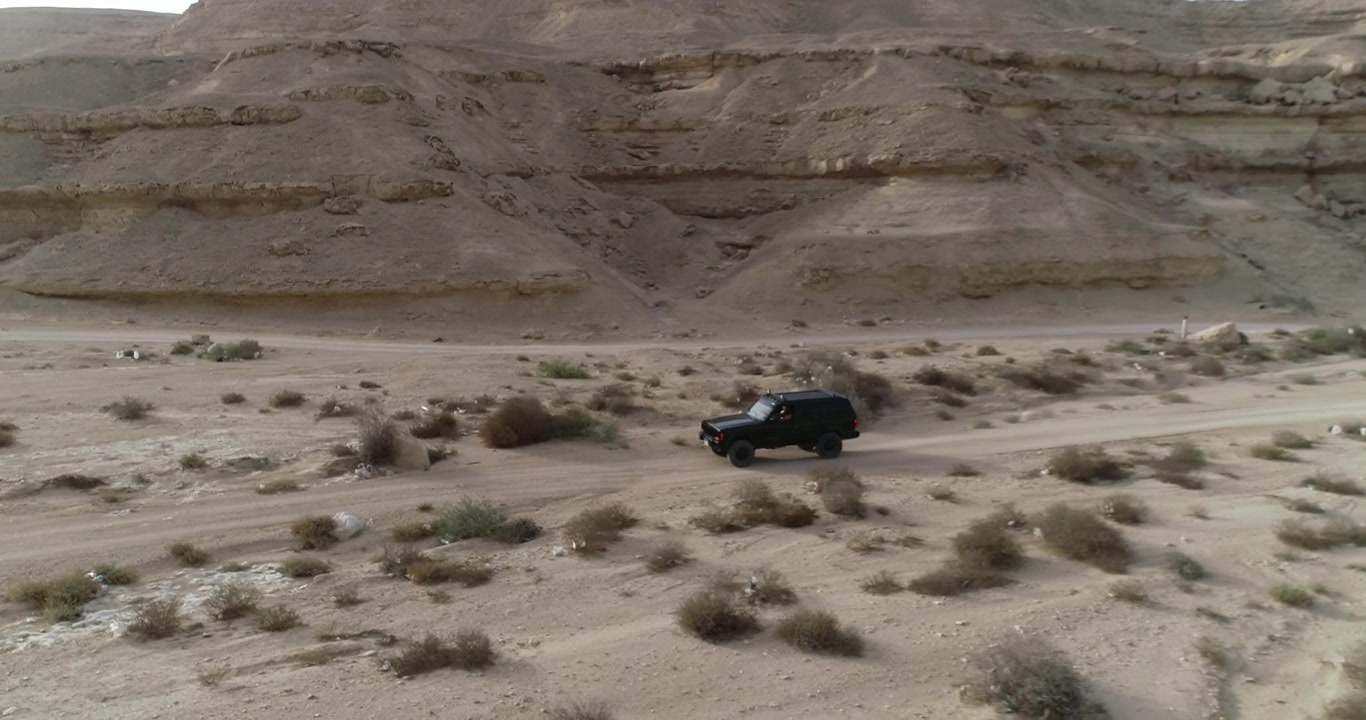 Ripresa con drone di un'auto 4x4 fuoristrada solitaria nel mezzo di una valle desertica nella Valle di Wadi Degla in Egitto.