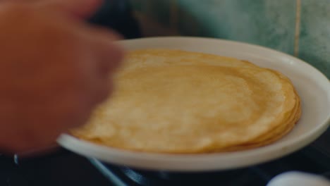 freshly made steamy pancake is placed on a plate from a hot pan in the kitchen