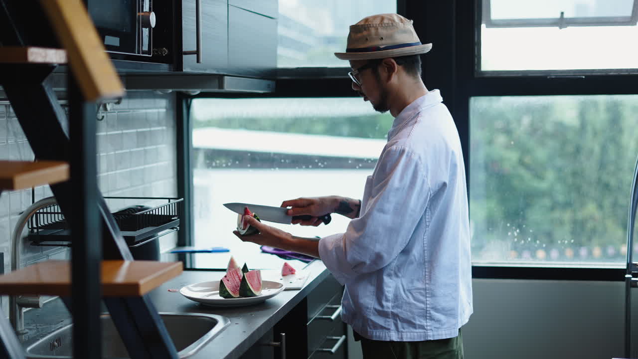 Um homem comendo melancia em uma cozinha