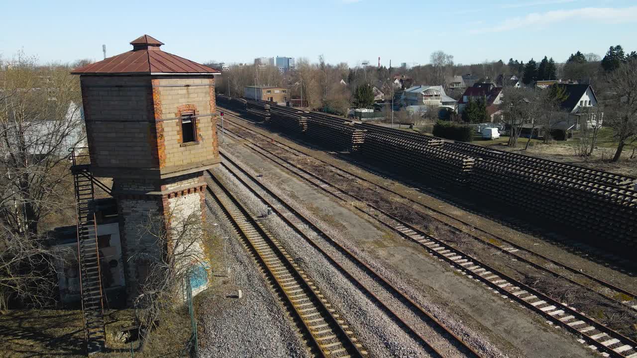 Aerial drone footage view ascending and revealing a large abandoned and old train constructor worker tower that is made out of bricks and is vintage. The building is close to railroad or traintracks.