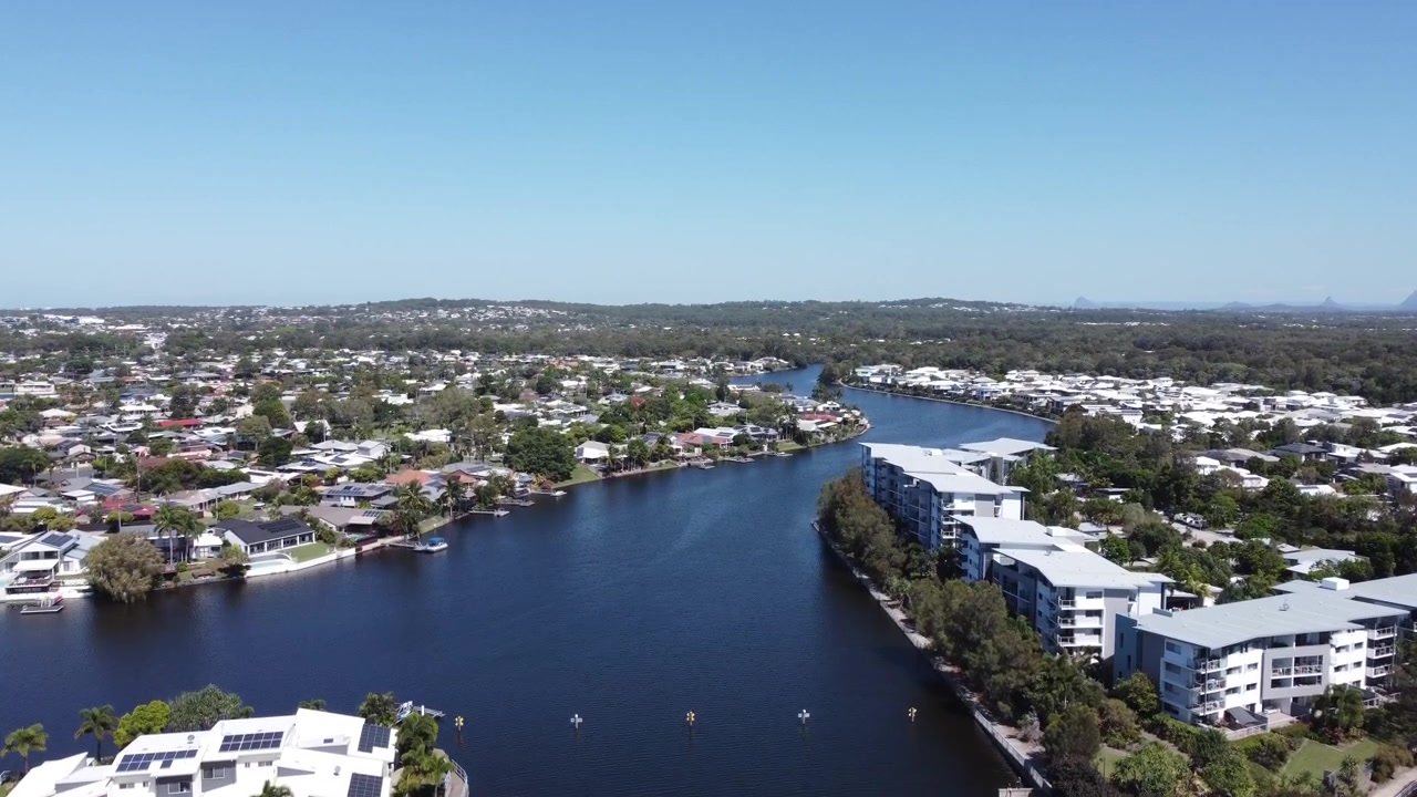 Drone nousee keinotekoisen kanavan yllä, jonka varrella on ylellisiä ranta-asuntoja ja huoneistoja Australiassa
