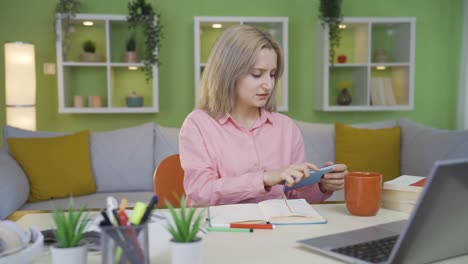 the young girl immersed in the game on the phone forgets the lesson.