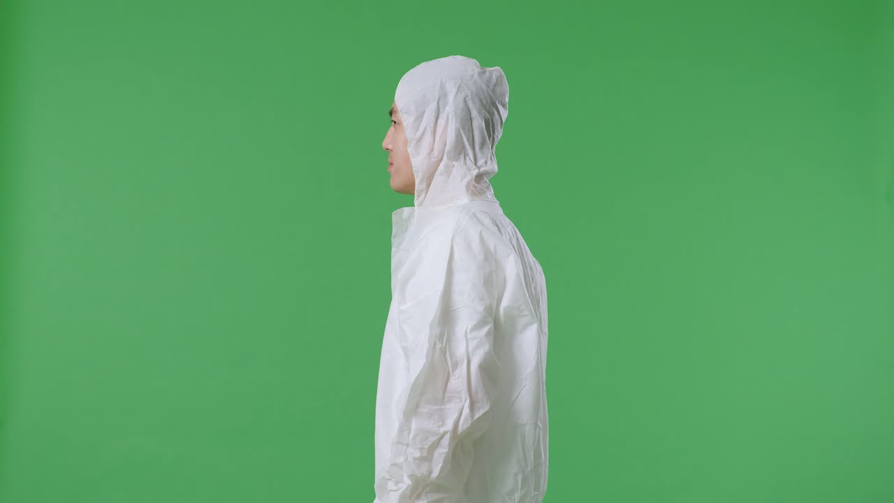 녹색 화면 배경에서 주변을 둘러보는 아시아 남성 과학자의 측면 시각