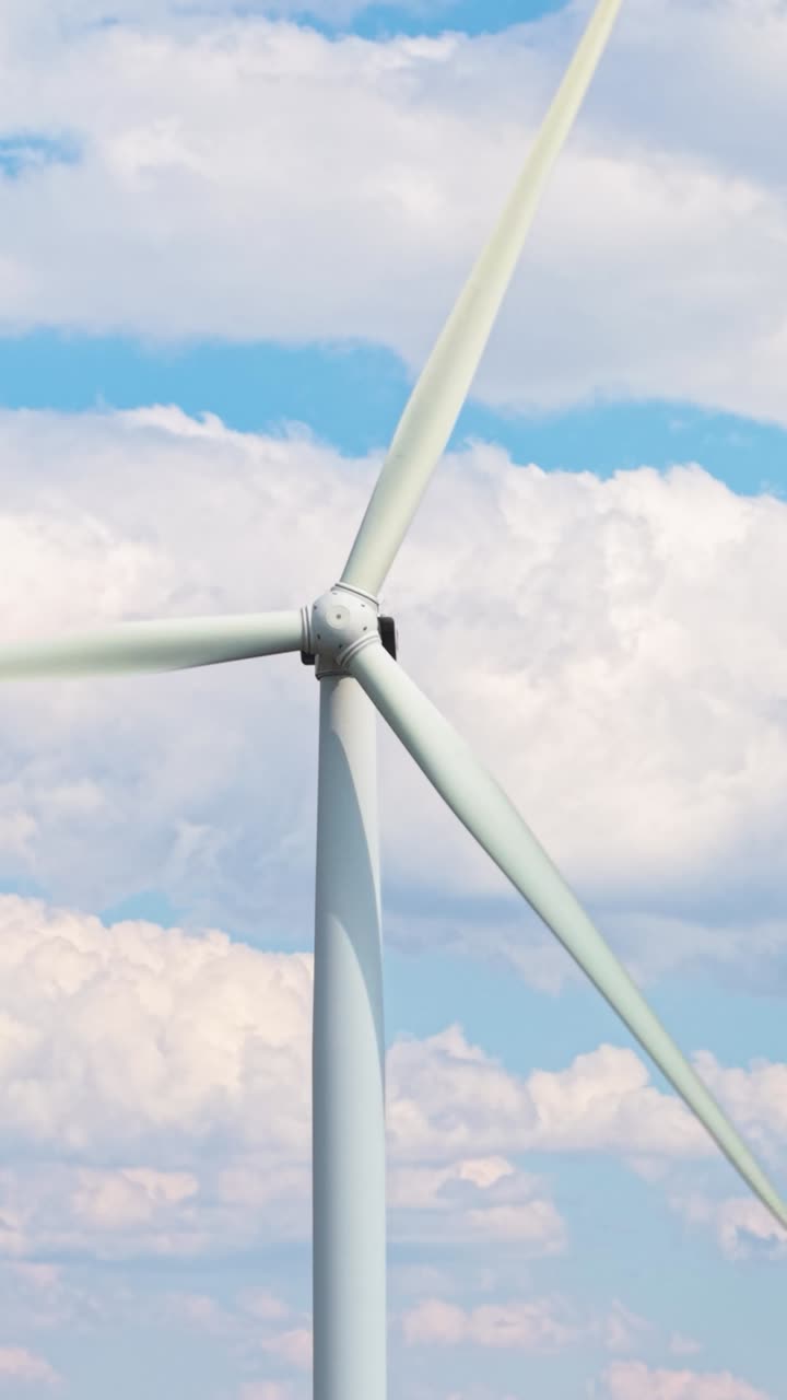 Smooth movement of wind turbine blades shot in vertical orientation with a stunning cloudy sky behind. Represents clean energy and environmental care