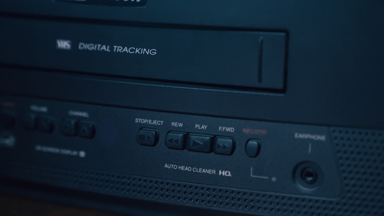 палец человека нажимает на кнопку воспроизведения на черном винтажном телевизоре и видеокамере