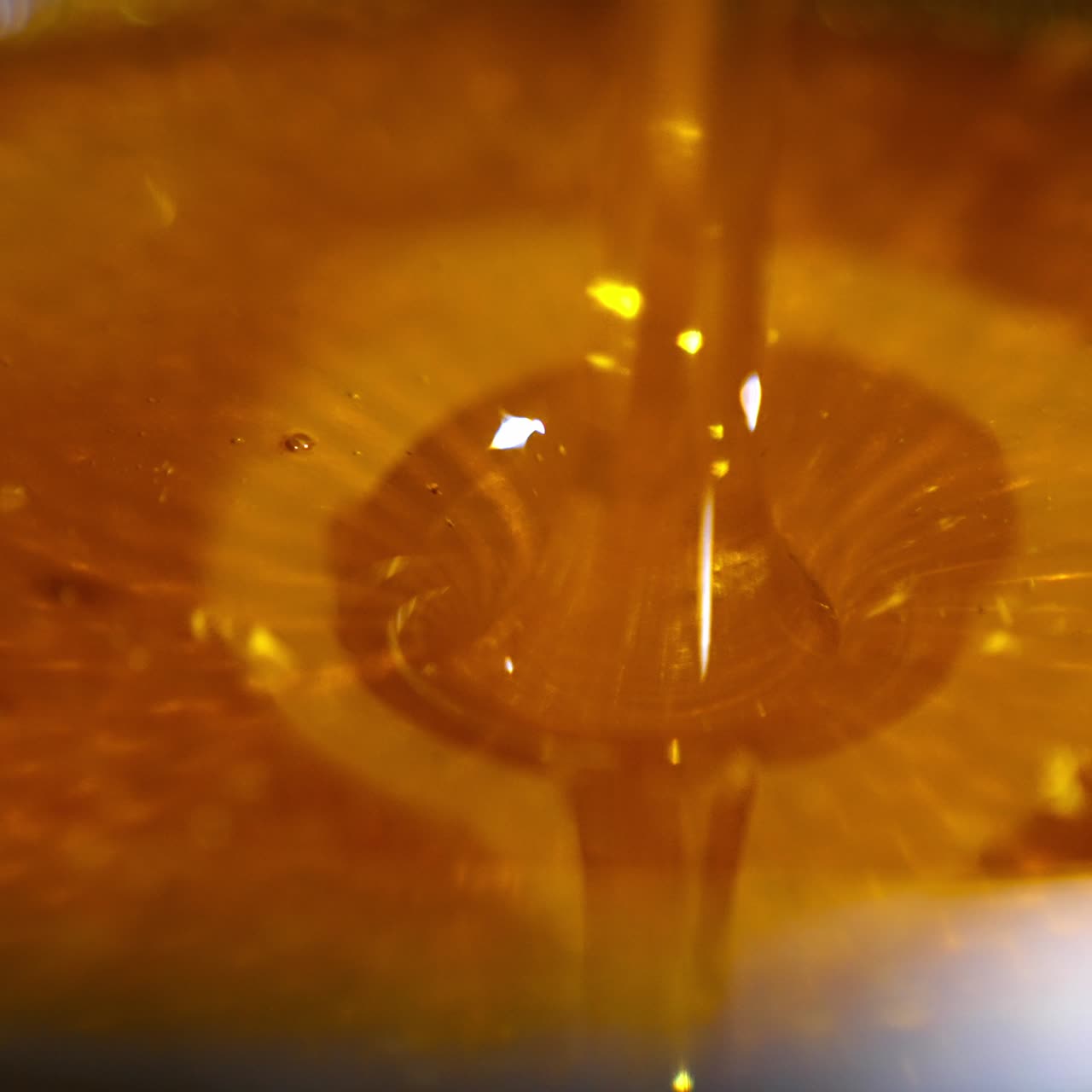 Unfiltered freshly extracted honey being poured onto metal sieve. Close up. Honey filtration after extraction