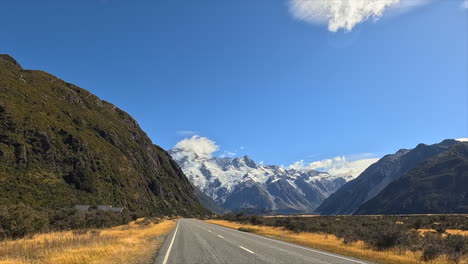 road leading to snow-capped mountains under a clear blue sky